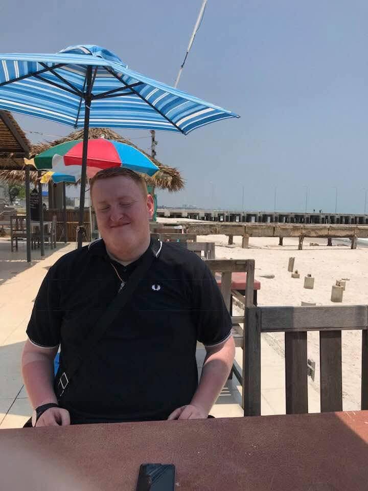 Justin seated at an outdoor table during a beach holiday