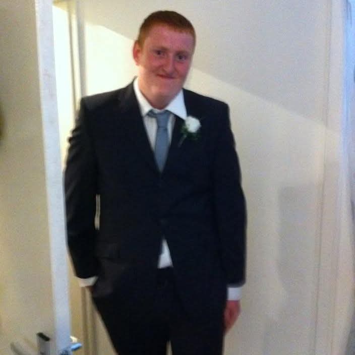 Justin standing in a suit indoors